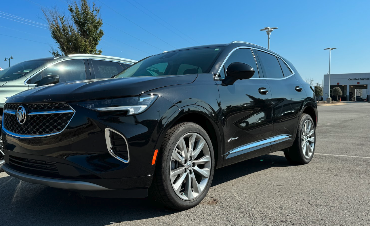 Glossy black 2024 Buick Envision Avenir SUV parked at Crain Buick GMC dealership in Conway.